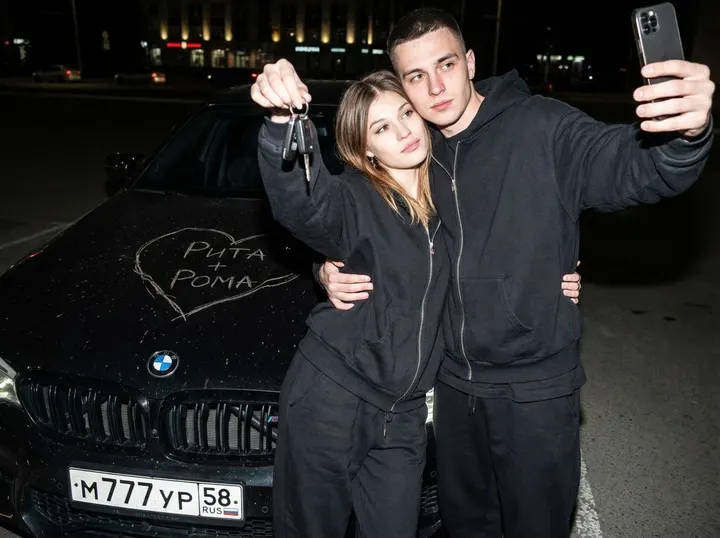Селфи пары у черного BMW с сердцами на капоте
