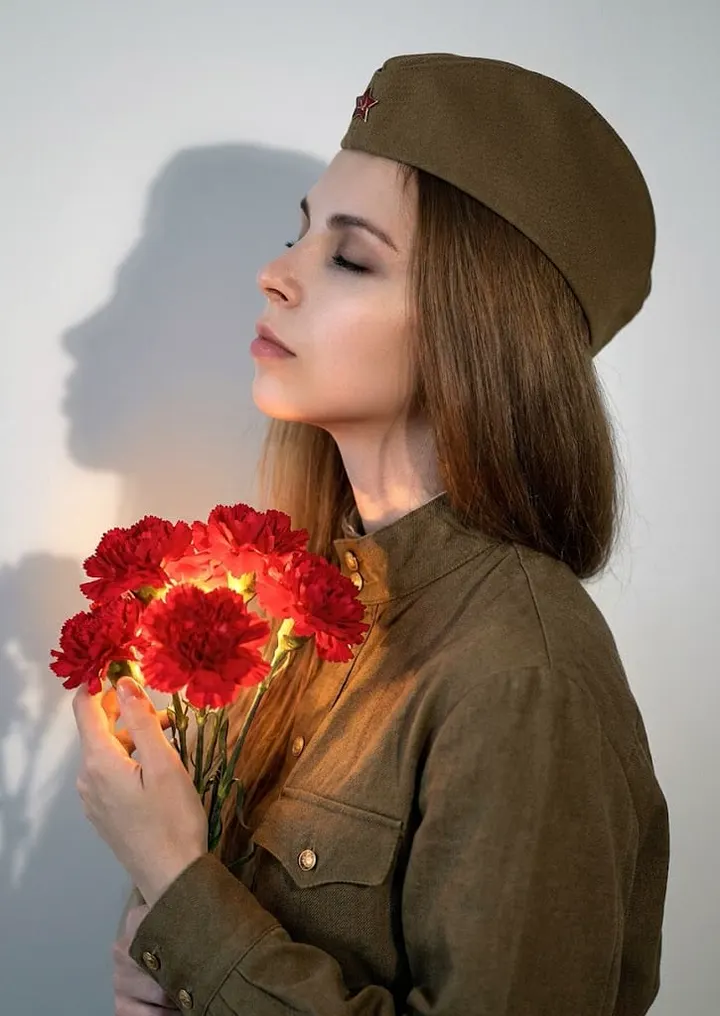 Женщина в военной форме с гвоздиками