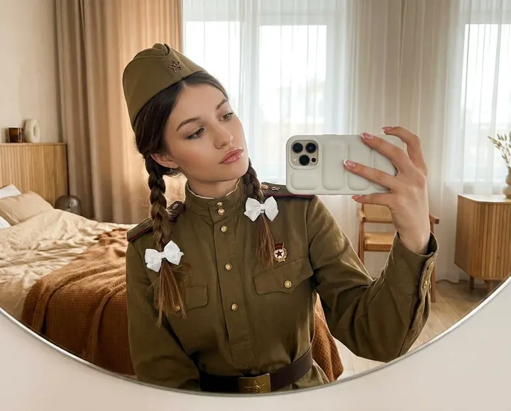 Девушка в военной форме у зеркала
